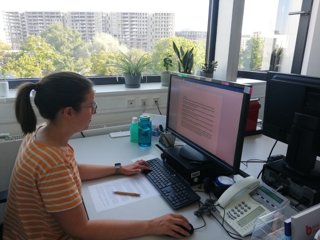 Claudia Wöckel sitzt am Schreibtisch und bearbeitet ein textdokument am Computer