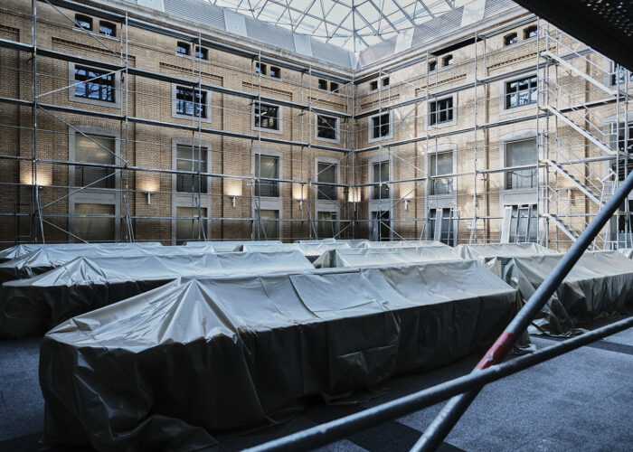 Blick in einen Lesebereich der Bibliothek. Die Tische sind mit dicken Planen abgedeckt, an den Wänden ist ein Baugerüst aufgebaut.